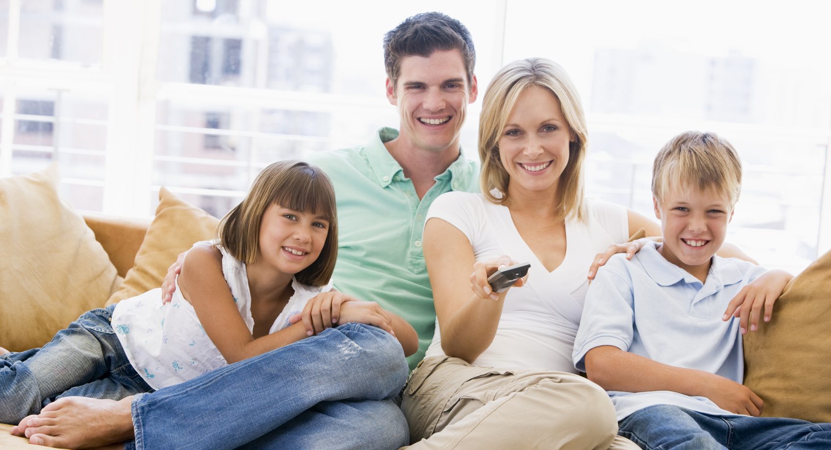 Family sitting in living room with remote control smiling