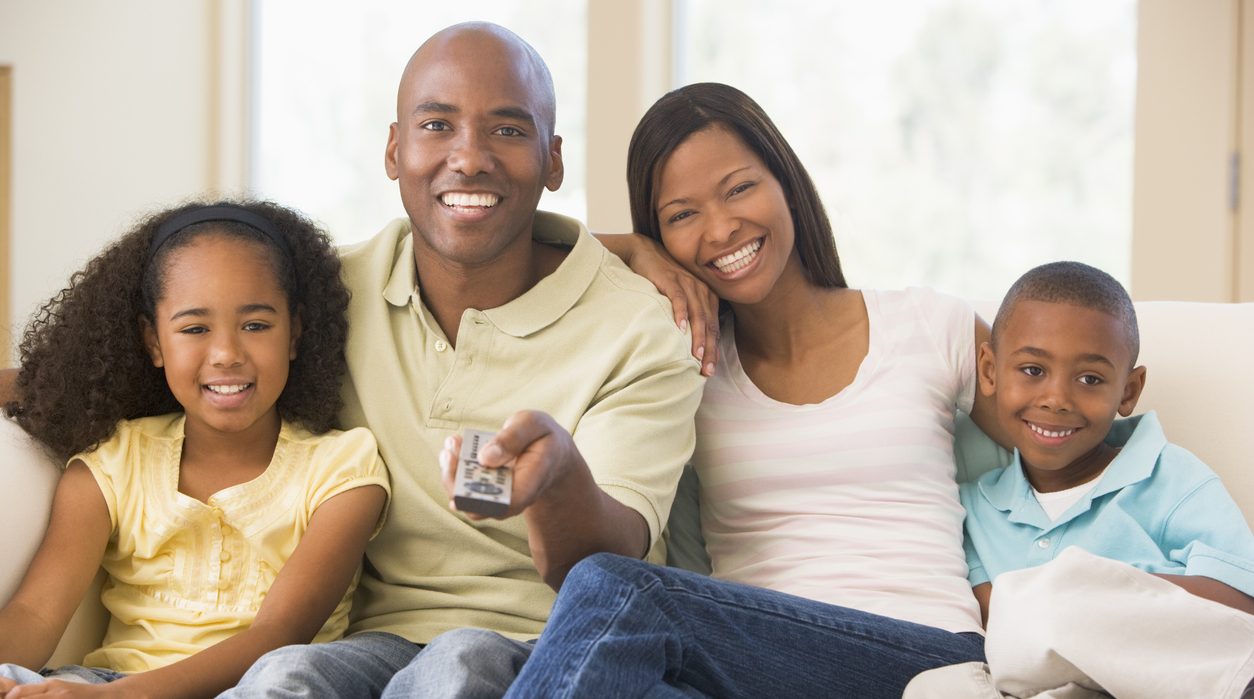 Smiling family sitting holding remote control